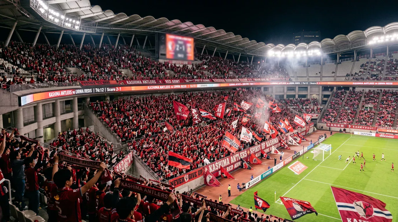 Estadio Noevir con aficionados del Vissel Kobe ondeando banderas carmesí durante un partido nocturno